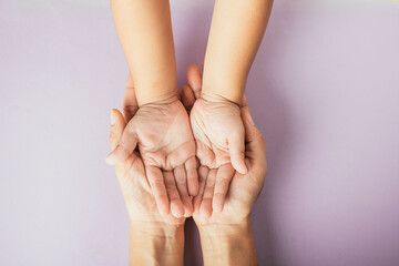 Closeup top view family hands stack palms studio shot isolated on purple background, parents and kid holding empty free space on hand together, Gesture sign of support and love, Family and parents day