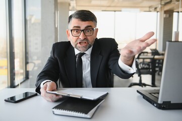 Fototapeta premium Angry businessman with document shouting at somebody
