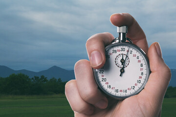 Woman holding timer in meadow, closeup. Space for text