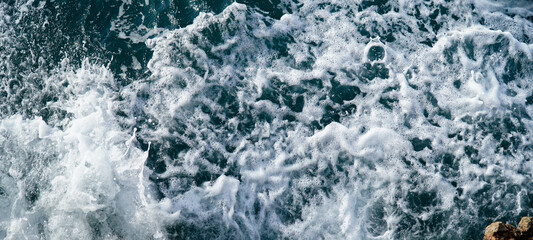 Fototapeta na wymiar closeup of wild ocean chaotic bubbles with foam in summertime. Sea textured in holidays