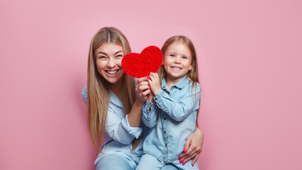 I love my mom. Mothers day .Close-up portrait little daughter and her mom with red heart on pink...