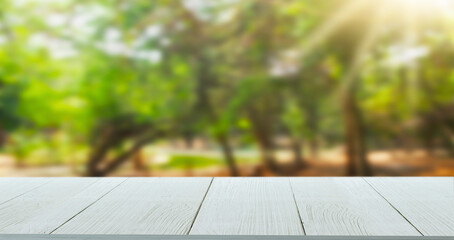 Wooden table top with forest natural green blurred background or various leaves, fresh bright sunlight, product empty concept.