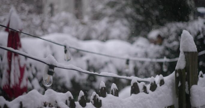 White fluffy snowflakes covering a wooden fence, electric wires. Winter storm, power outage concept