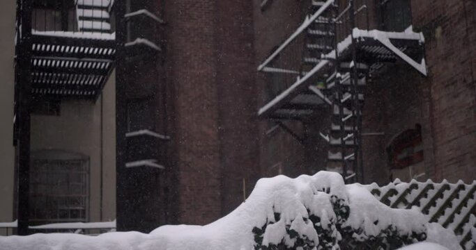 White fluffy snowflakes covering a fence, building and fire escapes.Concept winter storm, snowfall