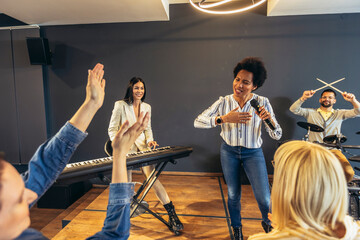 Business people making team training exercise during team building seminar singing karaoke.