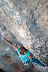 A woman climbs a rock