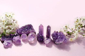 amethyst minerals set and white cherry flowers close up on abstract light pink background....