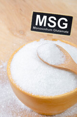 The monosodium glutamate, MSG in wooden spoon on wooden cup with text MSG.