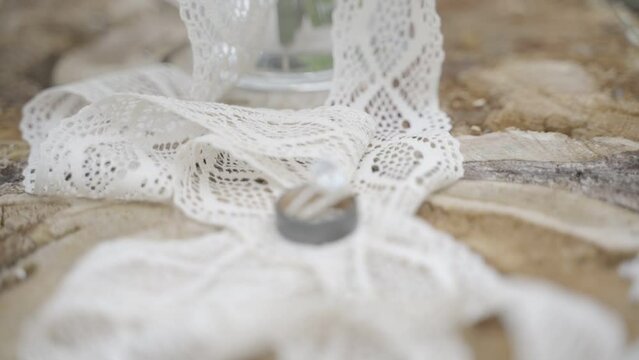 Closeup shot of a ring and a bouquet of roses tied with a white lace ribbon