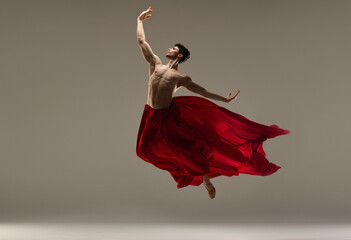 Young, athletic, handsome man, ballet dancer making performance with red silk fabric against grey studio background. Concept of art, classical dance, inspiration, creativity, beauty, choreography - obrazy, fototapety, plakaty