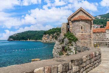 Fototapeta na wymiar Ancient tower of the Santa Maria in Punta Church against the backdrop of the seascape of the Adriatic Sea in Budva, Montenegro. View from the observation deck of the Old Town to a delightful scenery