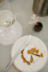 A cut head of cheese with almonds lying on it. There is a table knife on the plate.