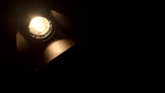 Video studio Fresnel lens spotlight on black background. Lights slowly turn on and off.