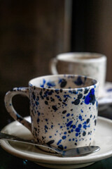 White coffee cup with blue spots on a saucer with a spoon on a wooden table