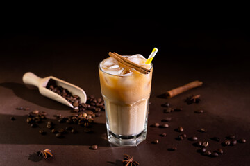 Cappuccino with Ice cubes in a tall Glass against a black background. Iced Coffee with milk in a glass