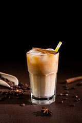 Cappuccino with Ice cubes in a tall Glass against a black background. Iced Coffee with milk in a glass