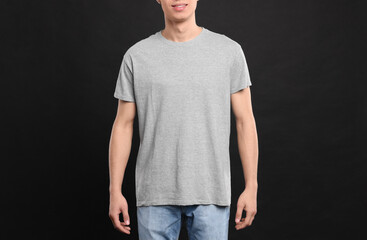 Man wearing light gray t-shirt on black background, closeup. Mockup for design