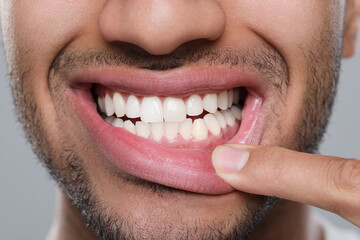 Fototapeta premium Man showing healthy gums on grey background, closeup