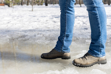 A man walks through a puddle in winter.