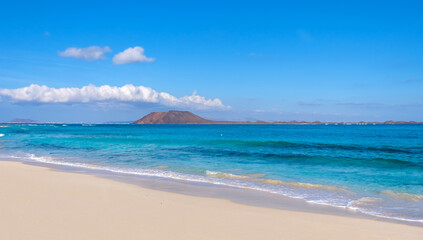View on Corralejo beach and Lobos island, blue water and golden sand and the Canary Island Fuerteventura, Spain.
