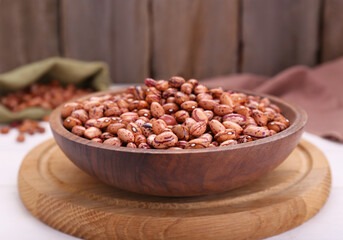 Bowl with dry kidney beans on white table, closeup