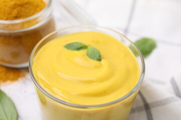 Glass with tasty curry sauce and basil leaf, closeup