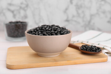 Fototapeta na wymiar Bowl of raw black beans on white wooden table