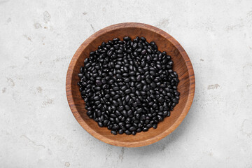 Bowl of raw black beans on light grey table, top view