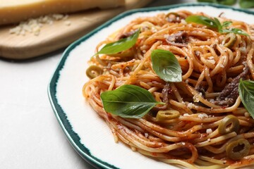 Delicious pasta with anchovies, tomato sauce and basil on white table, closeup