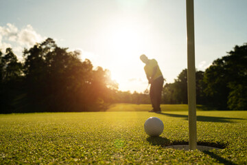 Blurred golfer playing golf in the evening golf course, on sun set evening time.