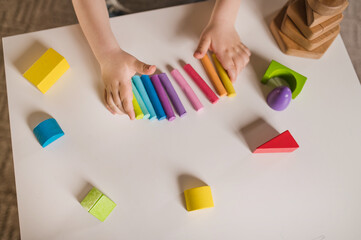 little boy three years old sits at  table with colored crayons and plasticine and plays sensory educational games. Closeup of hands focus on colored plasticine and constructor. Unrecognizable no face