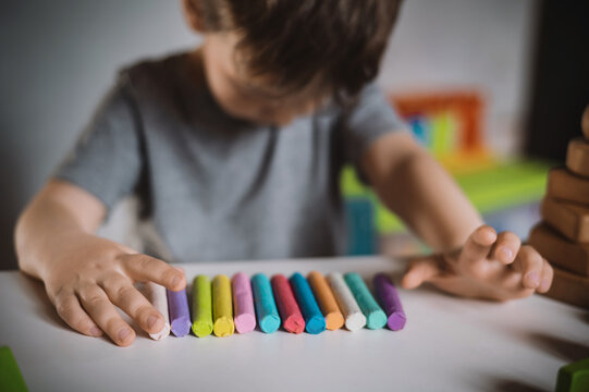 A little boy of three years sits at a table with colored crayons and plasticine lowered his head and cries. The kid is upset and stressed. Autism Spectrum Disorder and Adjustment Difficulties