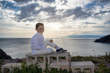 Unwavering Confidence: A Handsome Boy Poses on the Cliff at Sunset