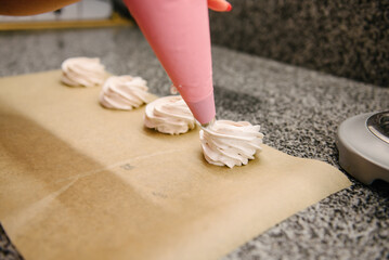 Confectioner from a confectionery syringe squeezes marshmallows onto parchment