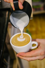 Barista pouring milk into a cup of coffee