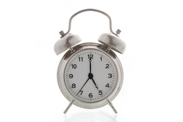 small metal alarm clock on a white background, time is 5 o'clock