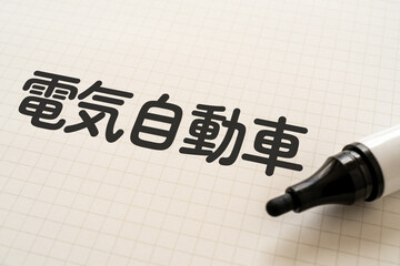 電気自動車と書かれたノートとマーカー