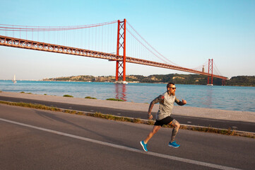 A man runs along the promenade of Lisbon in front of the April 25 bridge. Running in Portugal