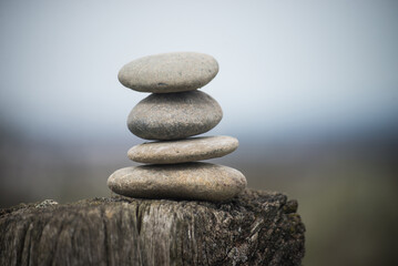 Fototapeta na wymiar Closeup of stone balance on a wooden fence in a field