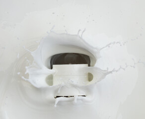 Naklejka premium Cosmetic container white lotion droplet fly splashing. Milk lotion pour float to cosmetic bottle. Moisturizer lotion explosion spill. White background isolated high speed shutter freeze top view