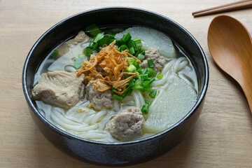 close up view of vietnamese rice noodles soup with pork in a ceramic bowl on wooden table. asian homemade style food concept.