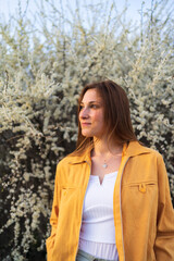 Portrait of young beautiful smiling woman standing by white blossom tree, spring time.