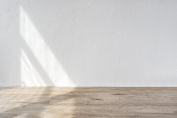 Aesthetic geometric sunlight shadows on white textured wall and beige wooden floor, empty template...
