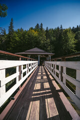 floating walkway made of wooden planks bridge, pier, narrow curved paths on stilts driven to the bottom above the lake water. more design sidewalk. Gazebo for relaxation. Vertical photo