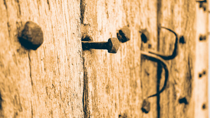 Selective focus shot of old rusty nails on a wooden wall with a sepia filter