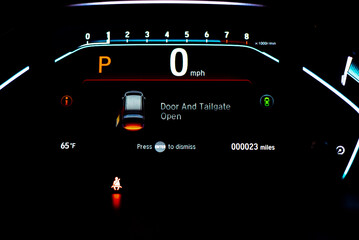 Red illuminated tailgate trunk open warning on instrument panel, dashboard control modern minivan car, low milage only 23 miles glowing LED indicator display