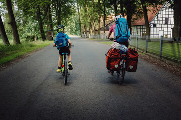 Mutter und Sohn radeln auf einer Landstraße während einer Fahrradtour durch das Münsterland in den Sommerferien, Deutschland