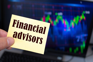 Male hand holding sticky note written Financial advisors.
