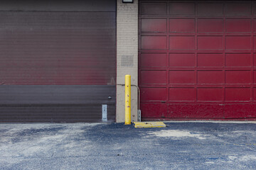 Two large red industrial garage doors and tired pavement