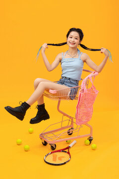 Energetic young girl sitting on shopping cart